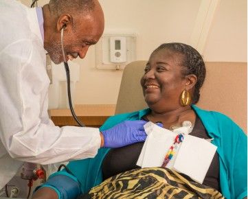 doctor listening to woman's heart in hospital bed